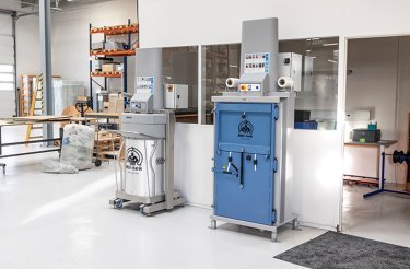 Pressa E119 accanto a un compattatore per rifiuti