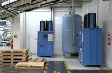 Due presse a balle Mil-tek installate nello stabilimento Trivium Packaging, affiancate da un serbatoio d'aria compressa e pallet in legno.
