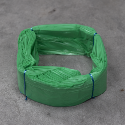 Fascio di sacchetti in plastica verde, legati con fascette blu, posati su una superficie grigia