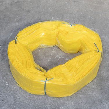 Fascio di sacchetti in plastica gialla XL, legati con filo blu, disposti a forma di anello su una superficie grigia
