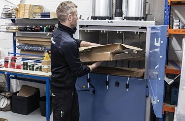 Un dipendente di Skjern Motorcycles inserisce cartone nella pressa a balle Mil-tek A406