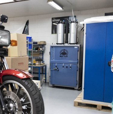 Vista generale del magazzino di Skjern Motorcycles con la pressa a balle Mil-tek A406, una motocicletta Kawasaki e attrezzature da moto